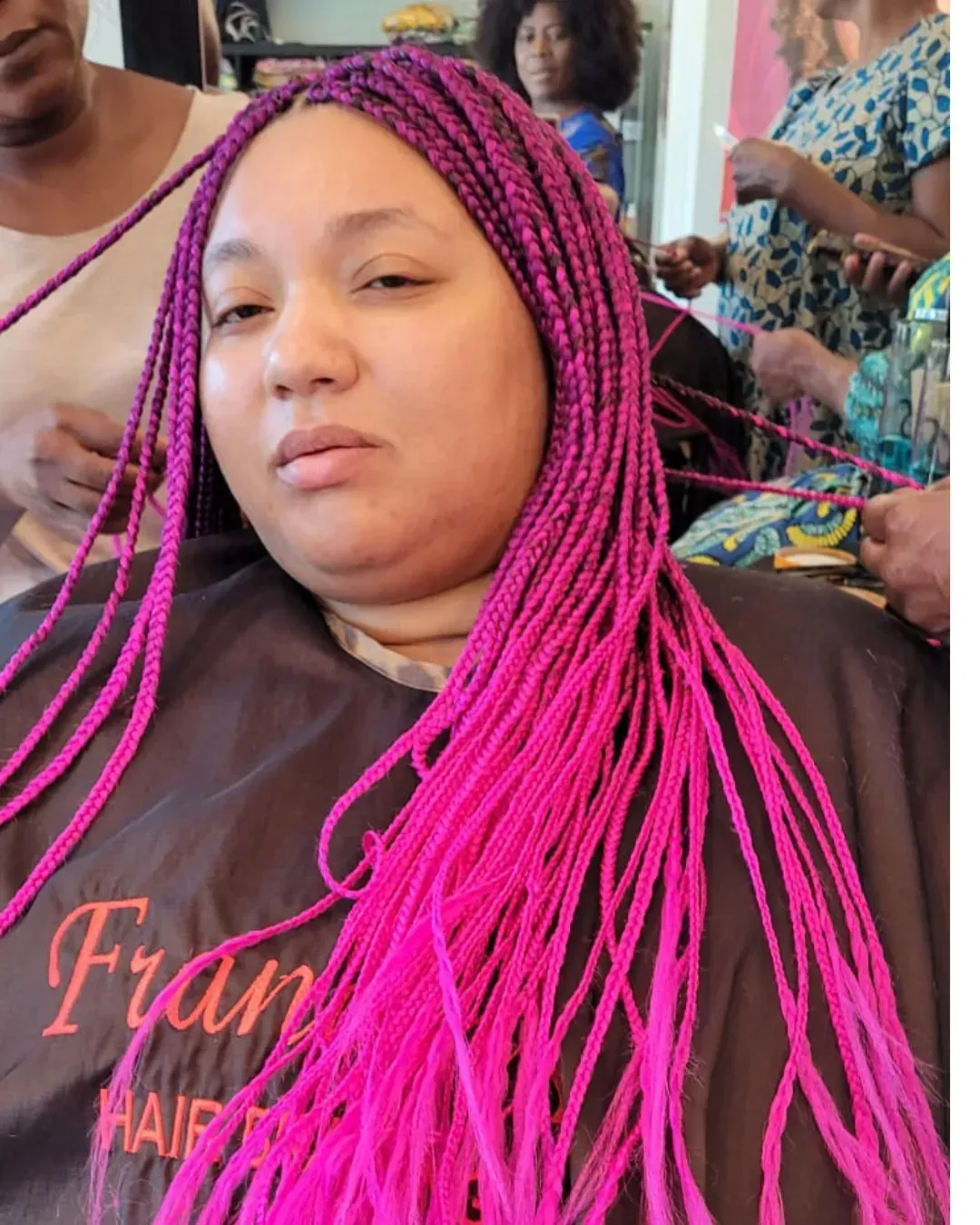 Woman with pink and purple braids getting her hair styled at a salon.