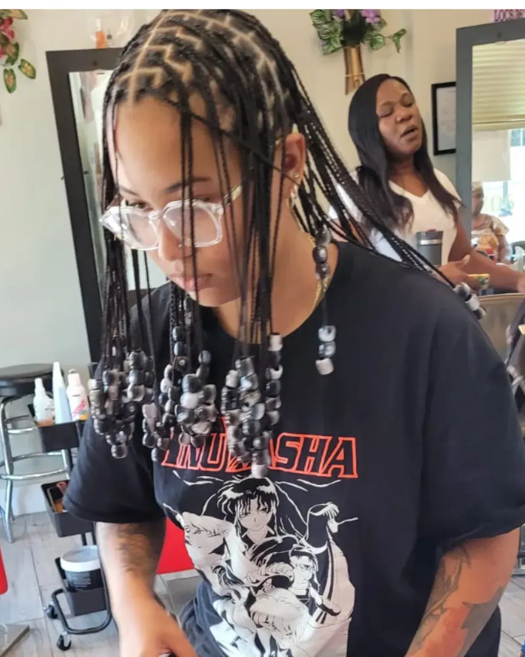 Person with beaded braids in a hair salon.