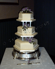 A traditional, hexagonal, three-tier white wedding cake.