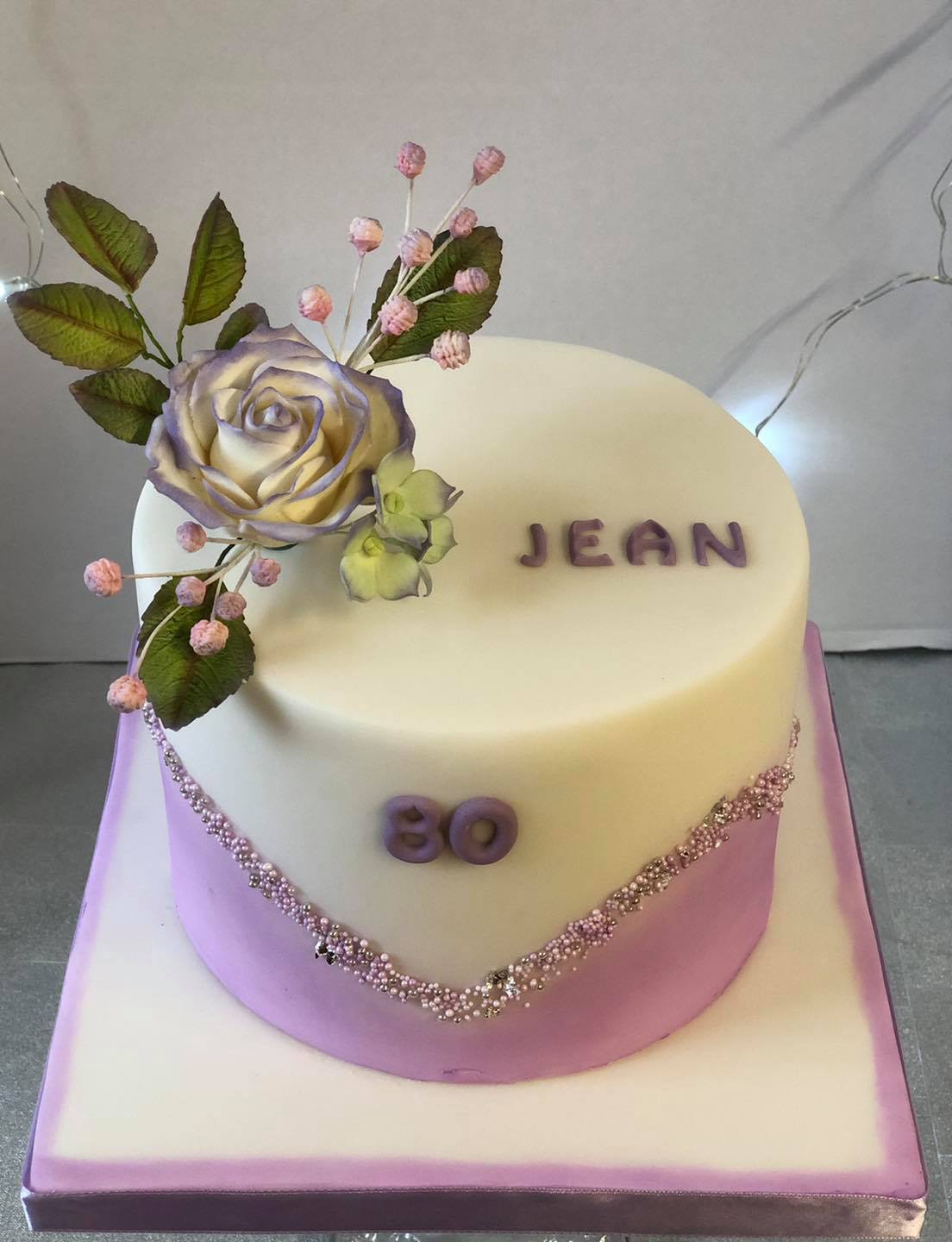 A professionally decorated white cake with the word