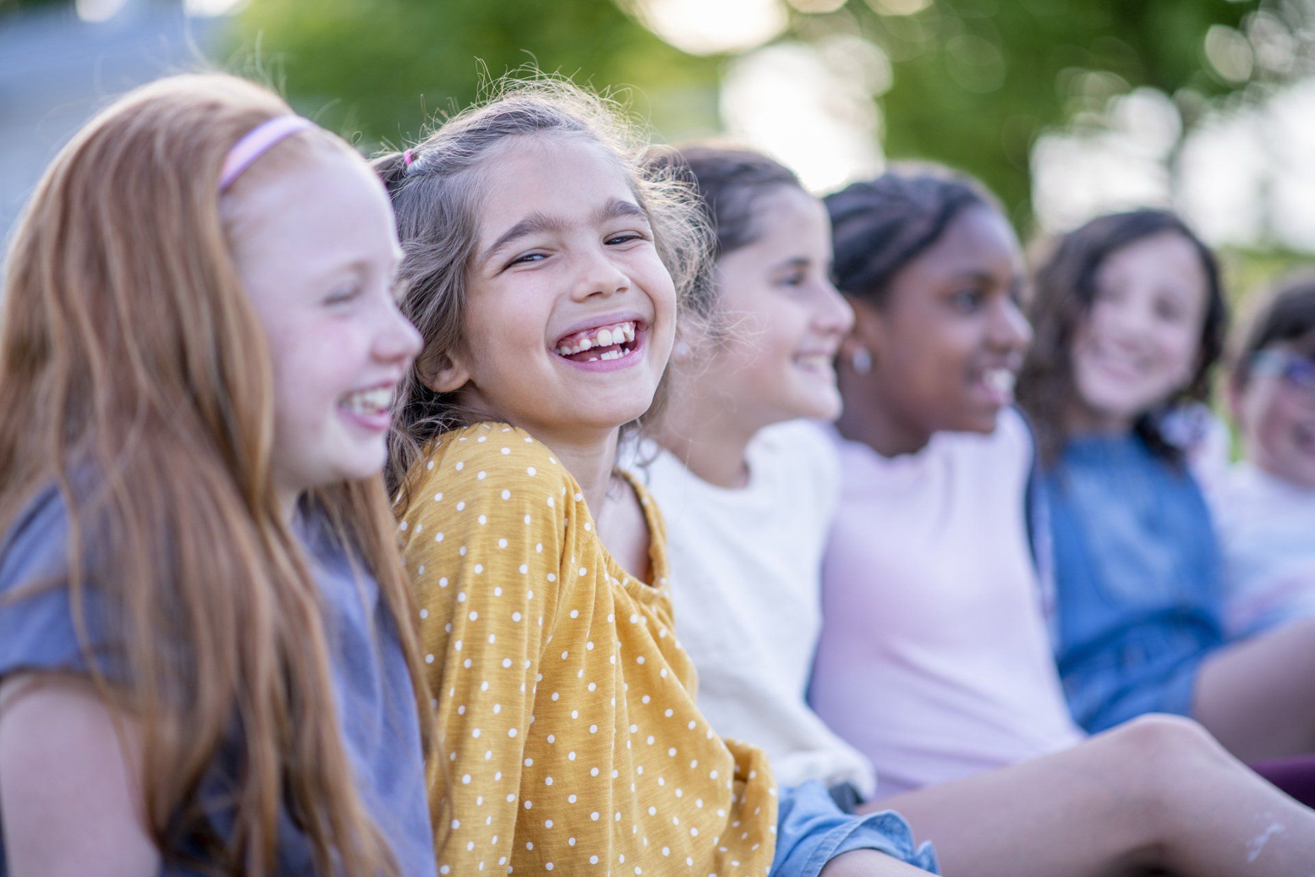 A group of young girls are sitting next to each other and laughing.