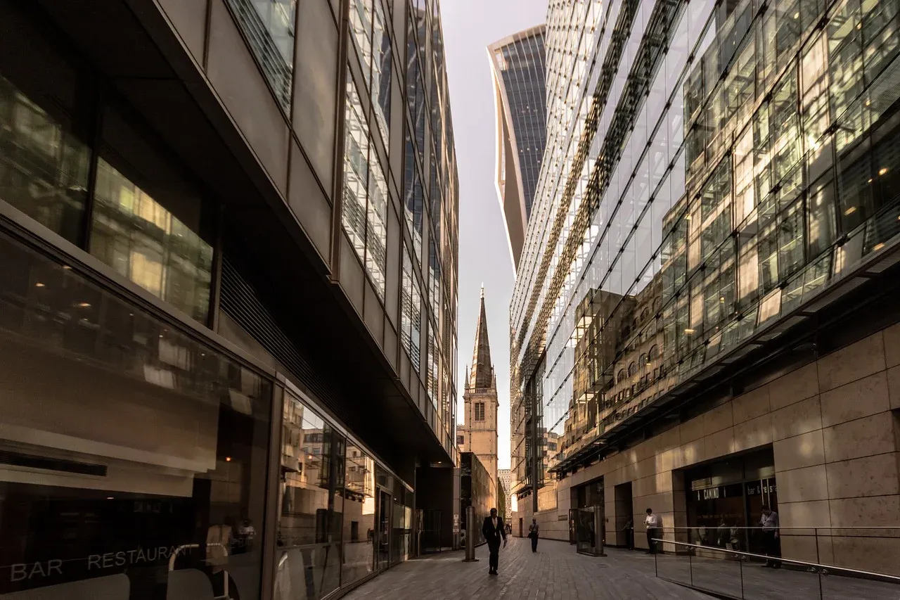 A narrow street between two tall buildings with a church in the background.