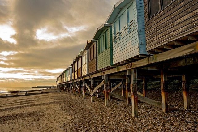 a row of beach huts on stilts on the beach .