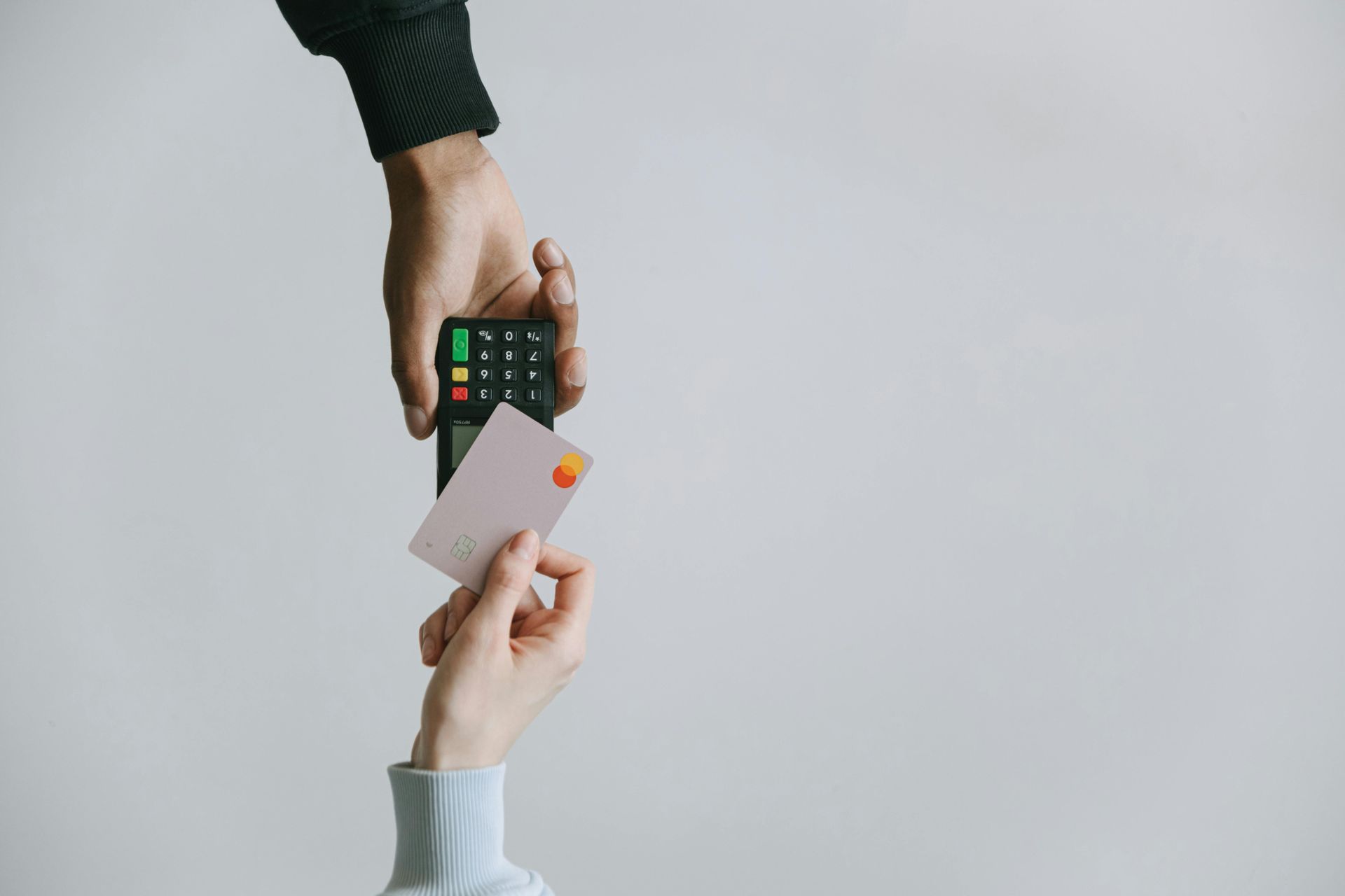 A person is holding a credit card and a credit card reader.