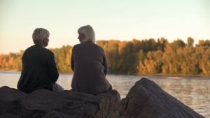 Adult women talking near lake in park, enjoying weekend outdoors
