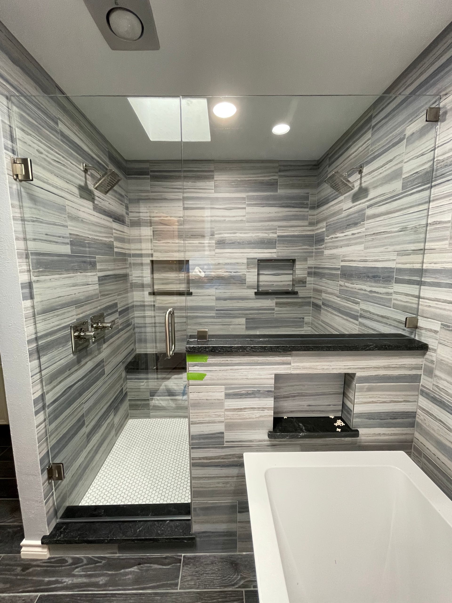Modern bathroom with glass shower doors and gray and white tiled walls.