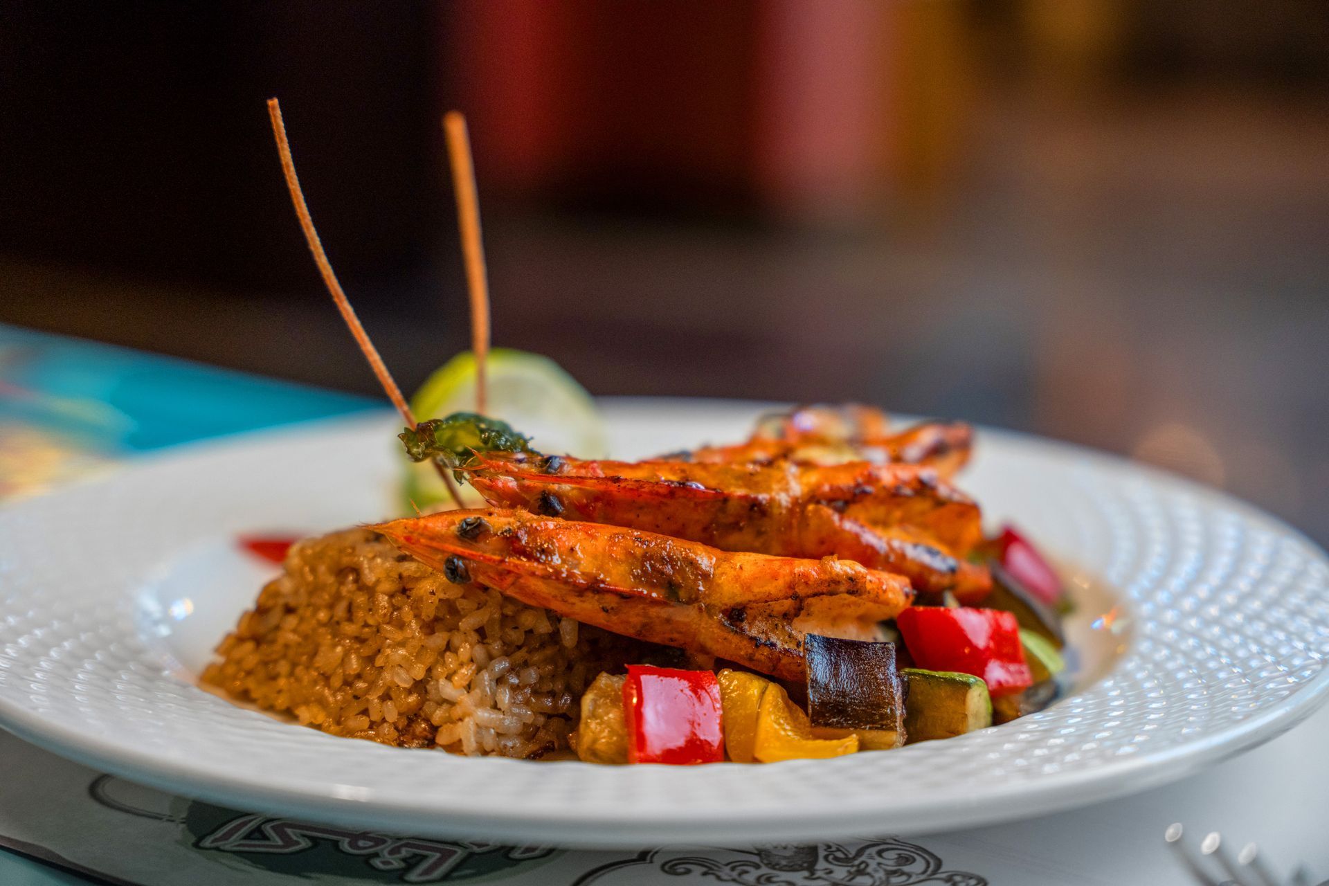 Grilled shrimp and vegetables over rice on a white plate.