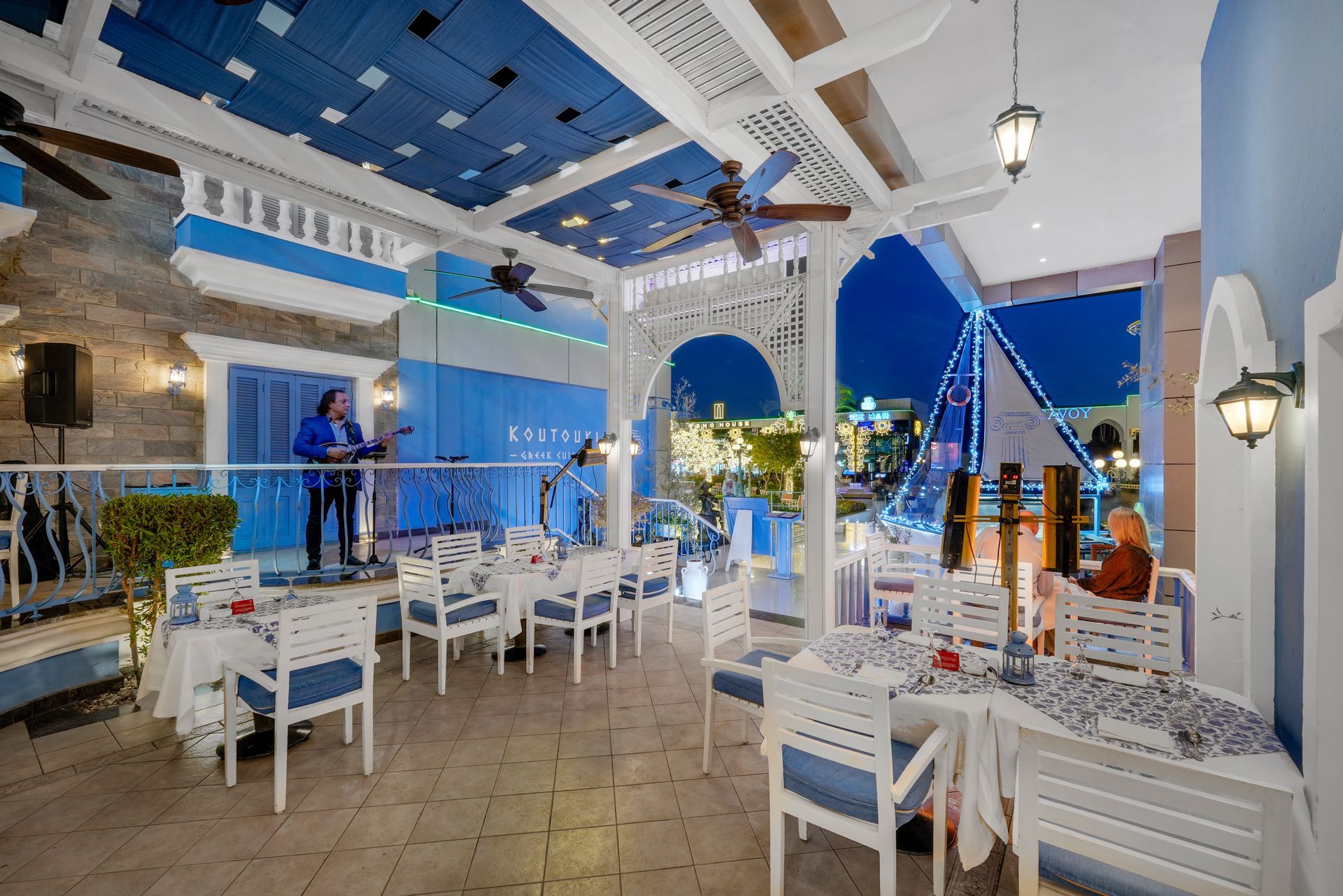 A restaurant with blue and white decor and a performer on stage. Evening setting.