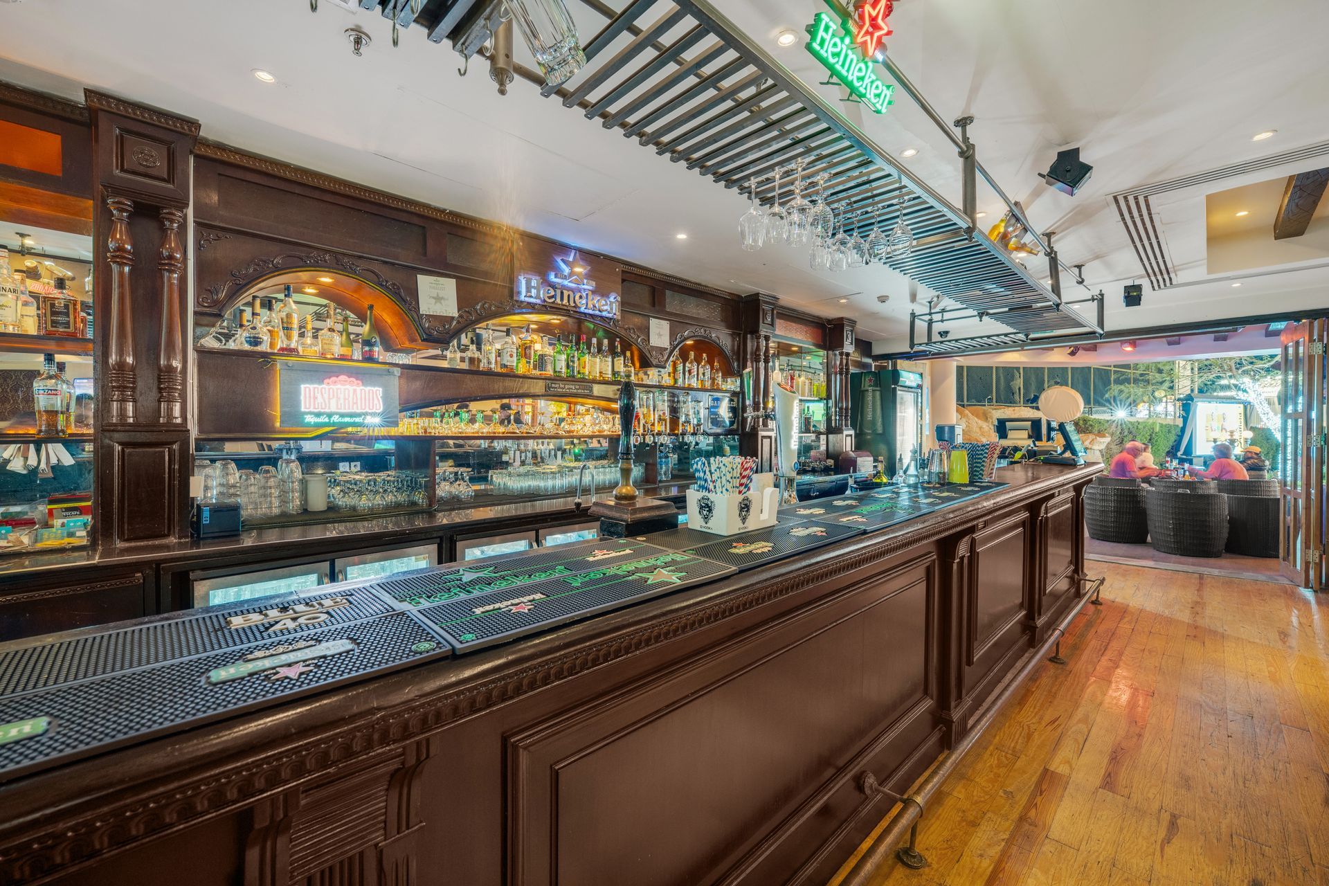 Bar interior with wooden bar, bottles, and neon signs.