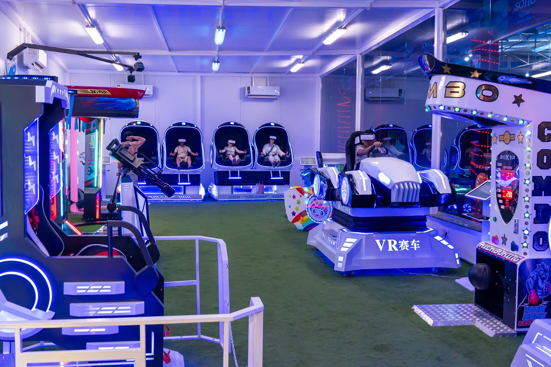 A colorful toy train and carousel illuminated at night in an outdoor carnival setting.