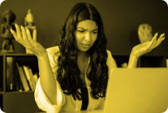A woman sitting in front of a laptop with her hands in the air