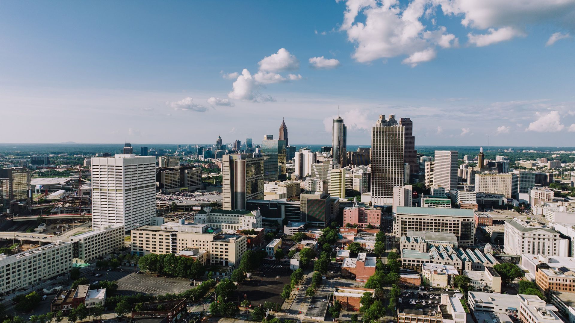 City skyline with modern high-rises under a bright blue sky with scattered clouds