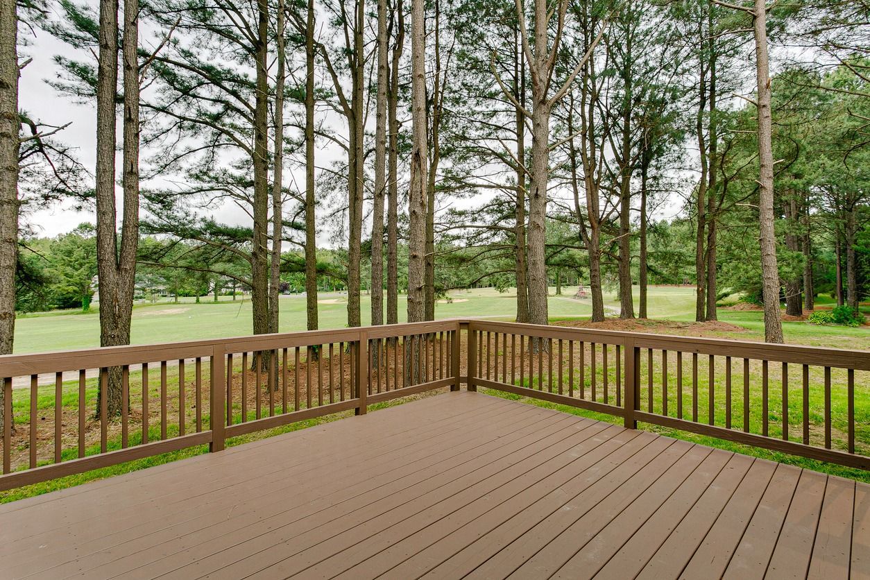 Wooden deck overlooking a golf course, framed by tall pine trees.