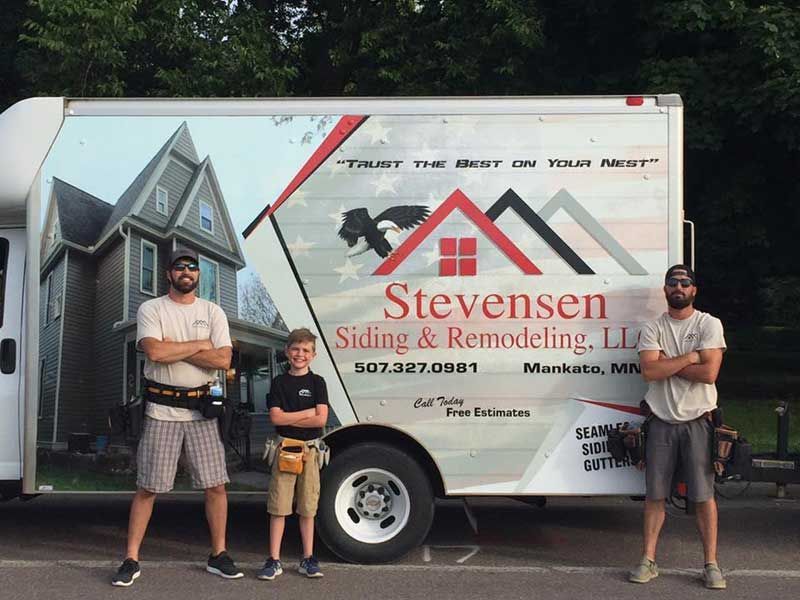 Three people standing in front of a company truck that says 