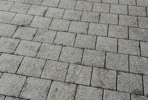 Graue Steinpflastersteine ​​in einem diagonalen Muster, die eine strukturierte Bodenoberfläche bilden.