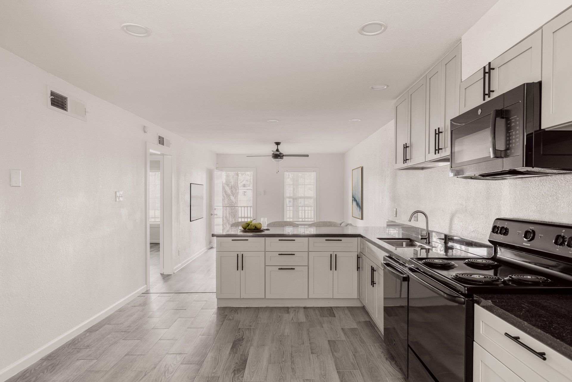 a kitchen with black appliances, granite countertops, and luxury plank flooring in Houston apartment