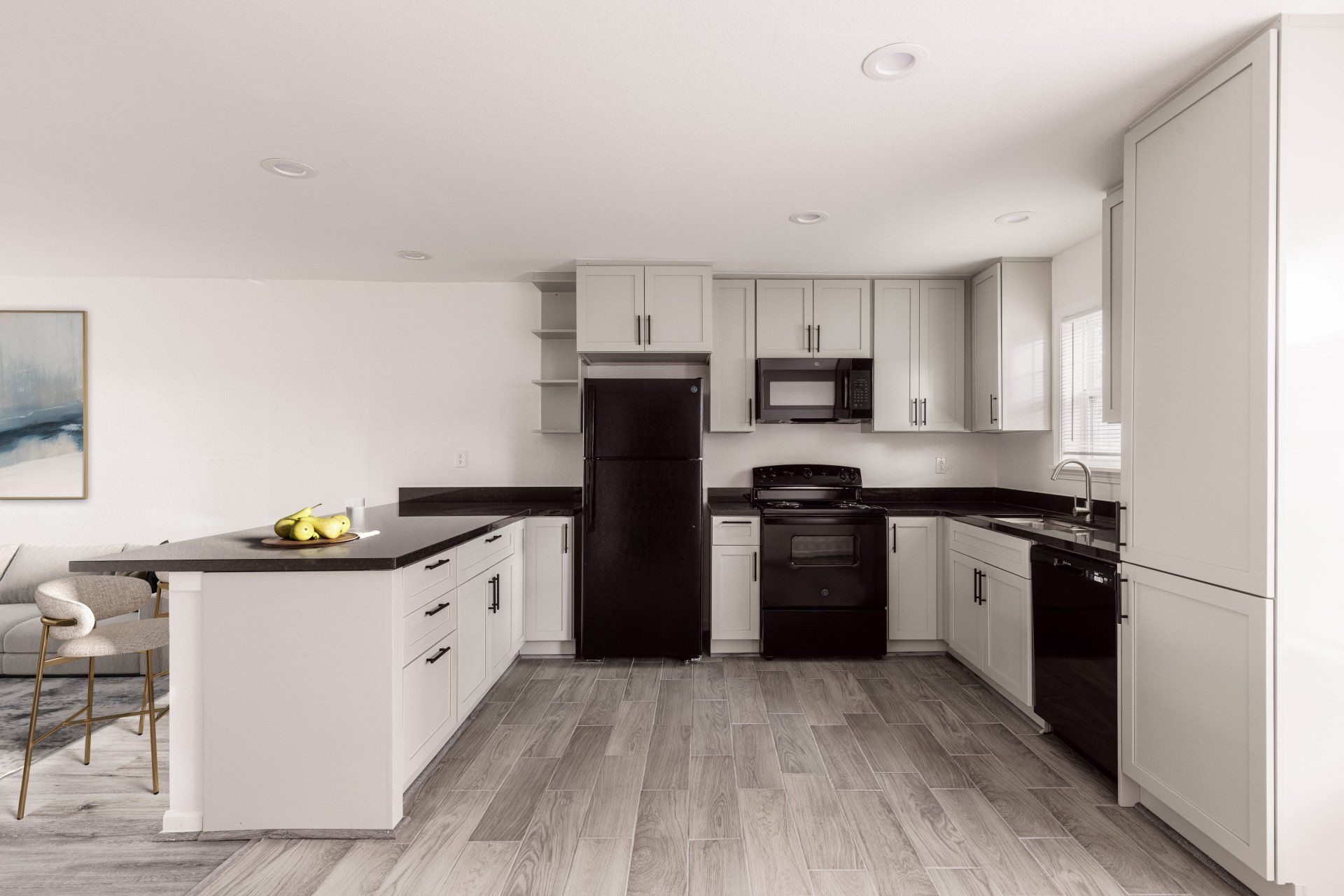 A sleek kitchen with gray cabinets and modern black appliances at Stylish Houston TX apartments at Gia Memorial