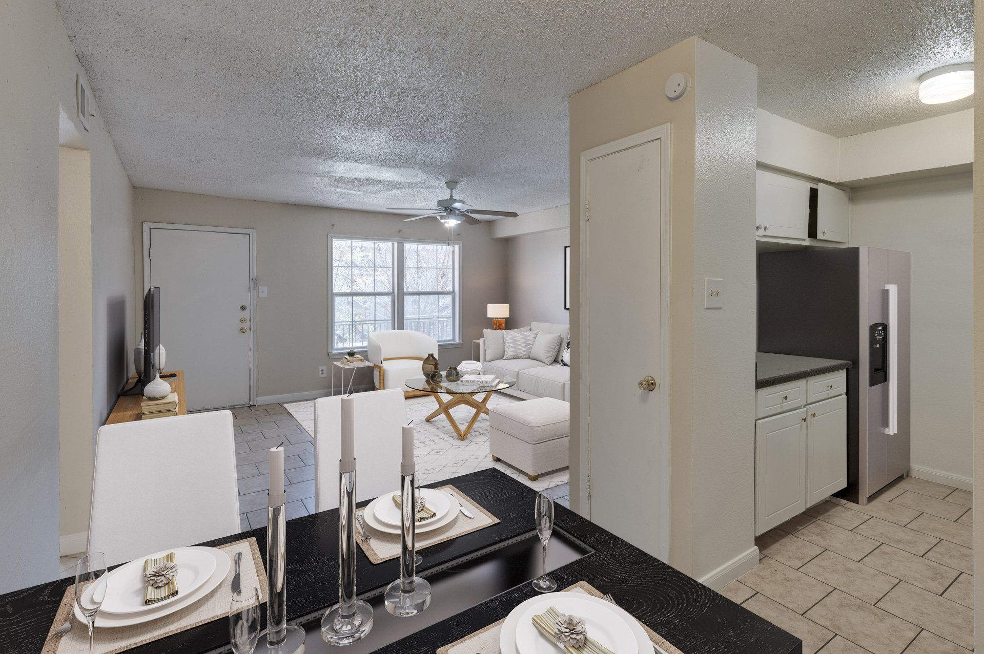 Bright, open-concept kitchen/living in a modern Houston apartment for rent, with dining set, fridge, sofa.