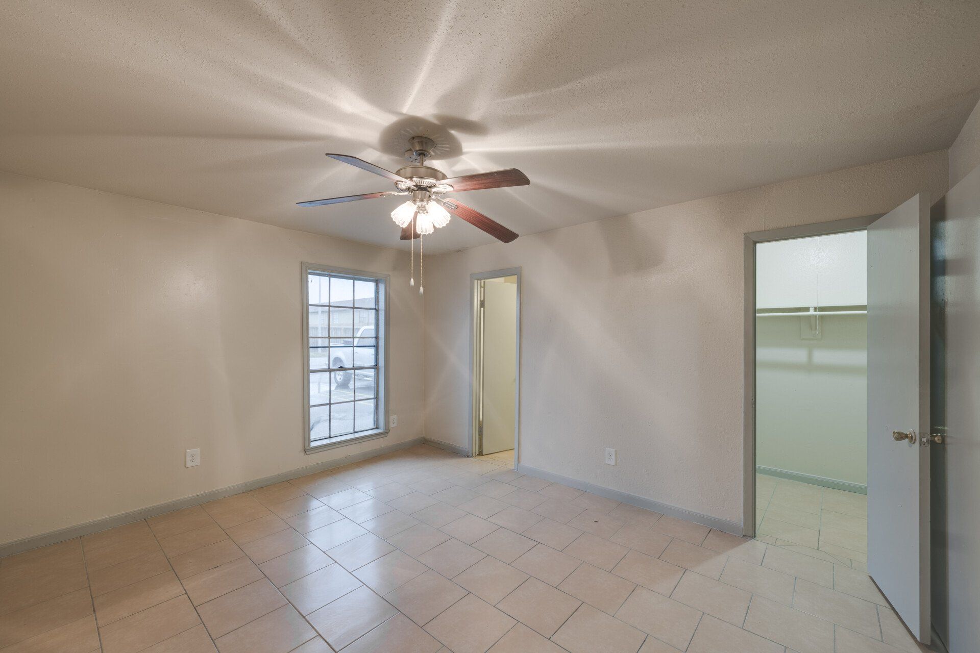 Serene bedroom in a Houston apartment for rent, with a spacious walk-in closet and tile flooring.