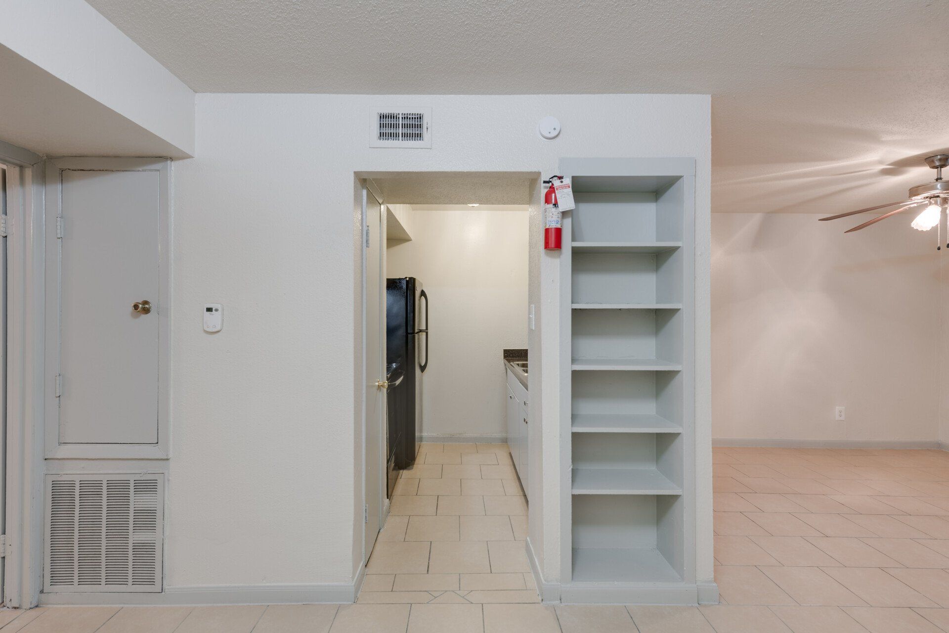 Houston apartment kitchen with full-size black refrigerator, stove, and adjoining dining area.
