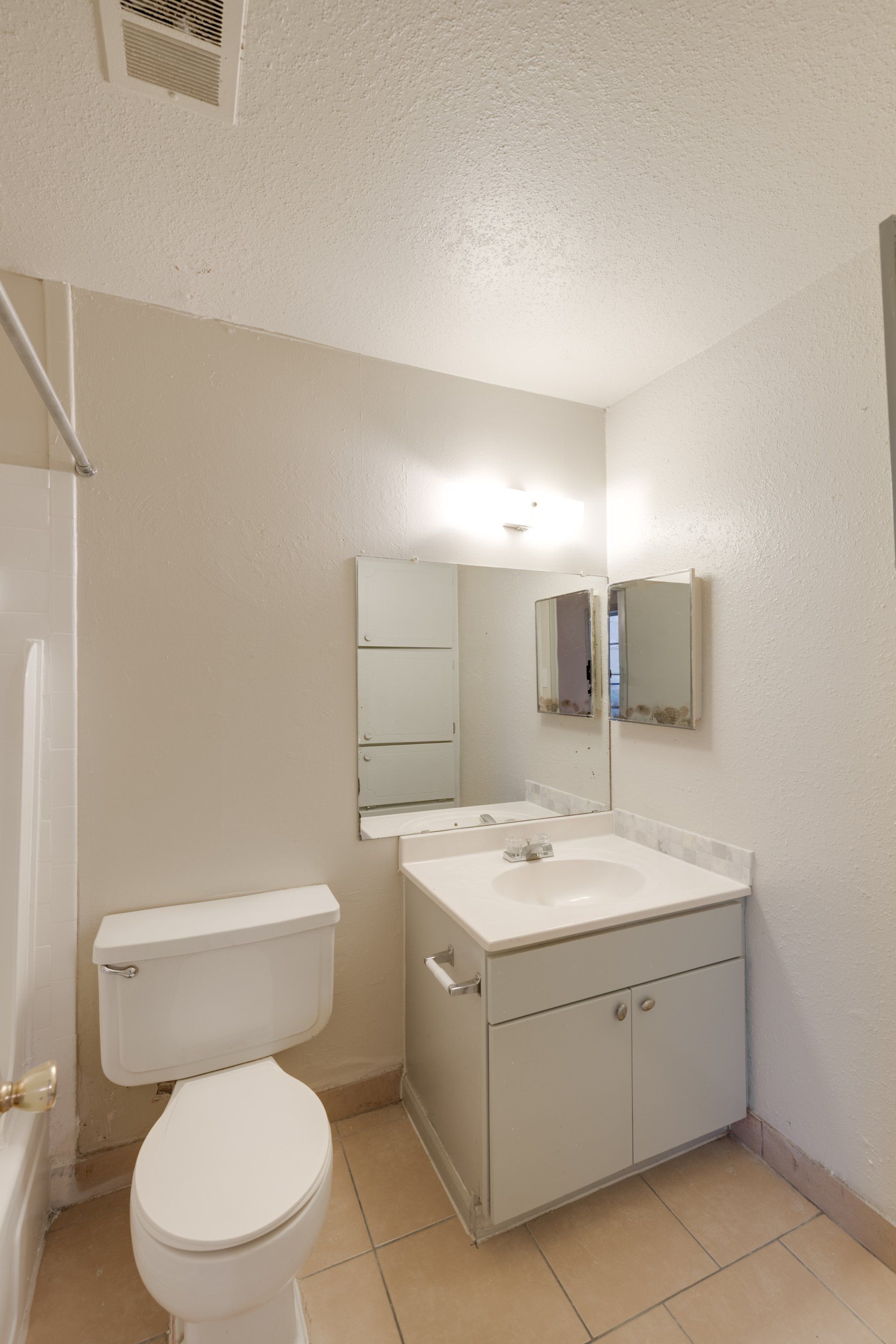 A bright, modern bathroom in a Houston, TX apartment for rent, with a vanity, large mirror, and tile flooring.