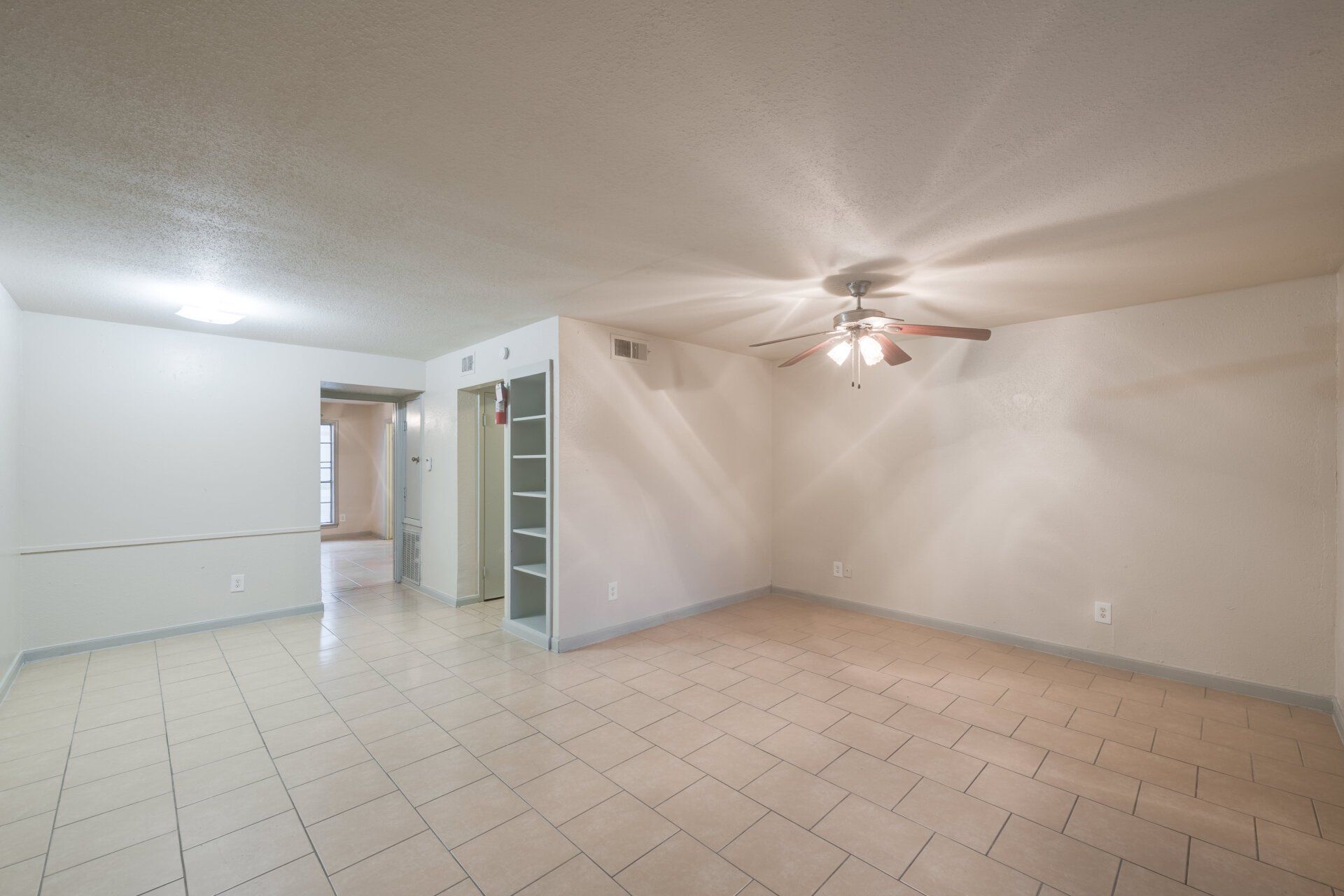 Spacious, open-concept living area in a Houston apartment for rent with tile flooring and a ceiling fan.