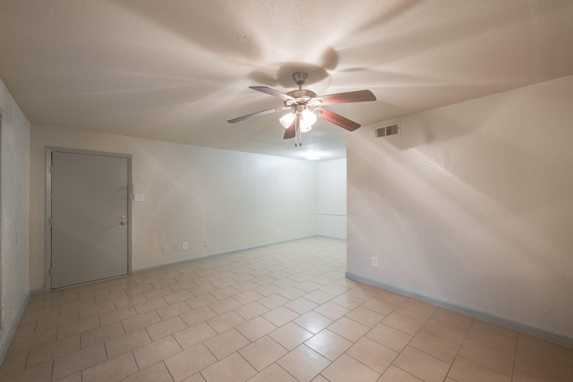 Spacious living room in a Houston apartment for rent with tile flooring and a ceiling fan.