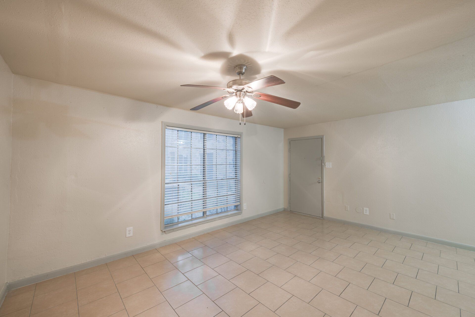 Bright, spacious living room in a Houston apartment for rent with tile floors and ceiling fan.