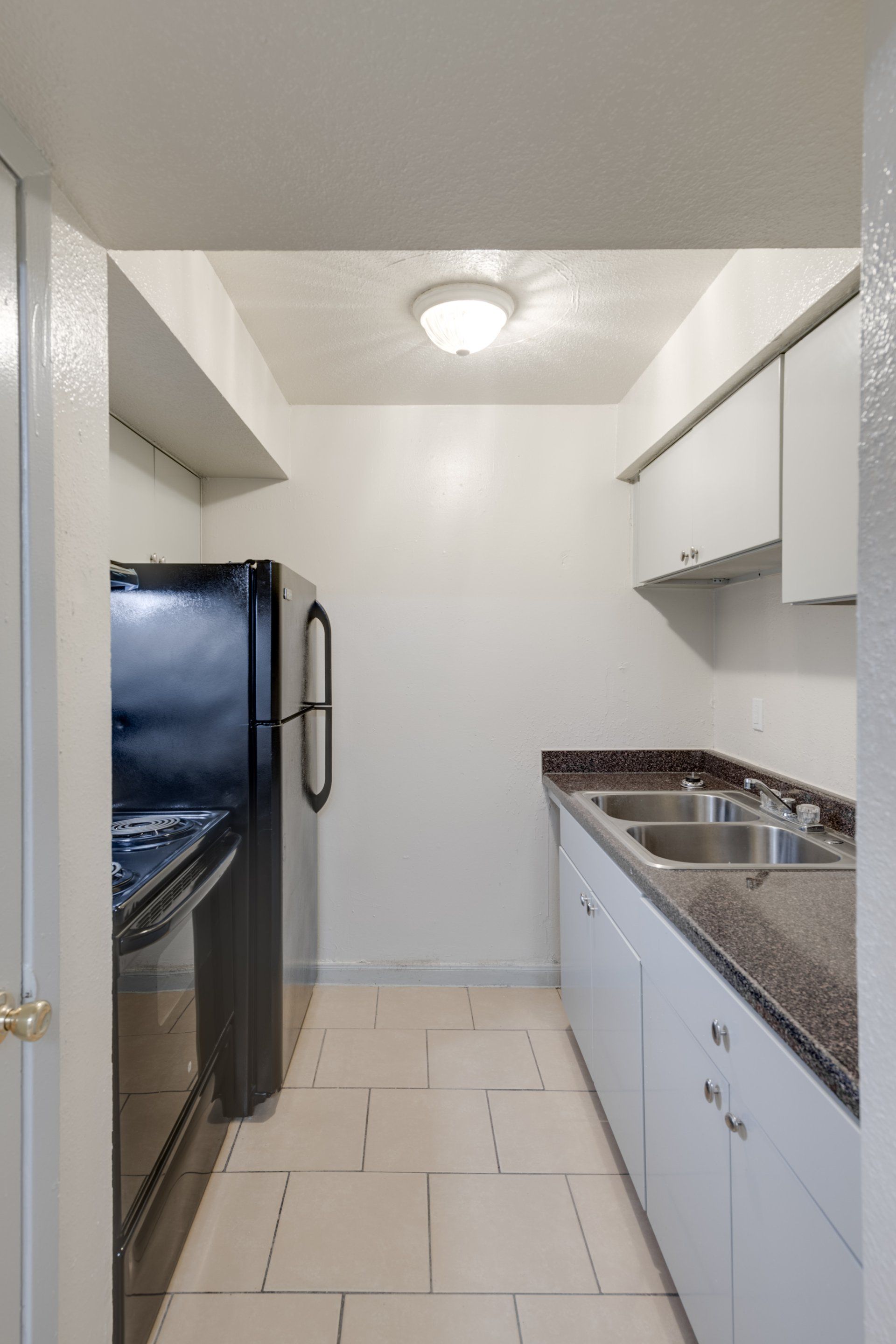Modern kitchen in our Houston apartments with granite counters, white cabinets, black appliances.