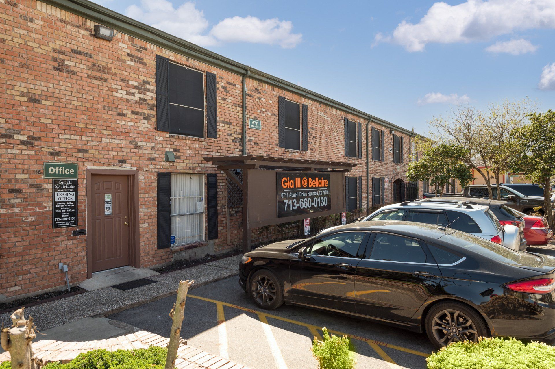 Signage for move-in specials at Gia III Bellaire, a brick community with Houston apartments for rent and parking.