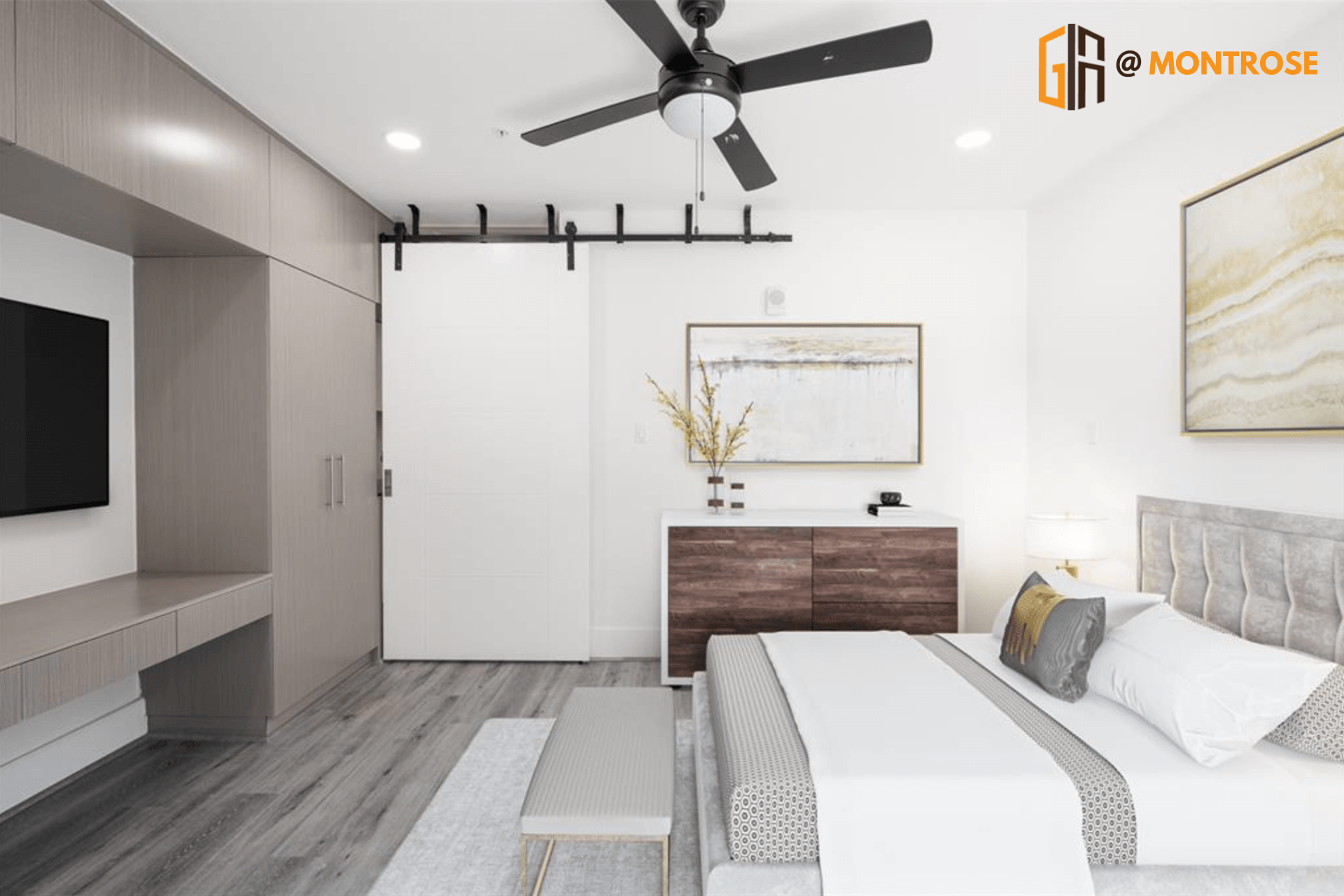 Modern Houston apartment one-bedroom for rent featuring a queen bed, sliding barn door, and wall-mounted TV.