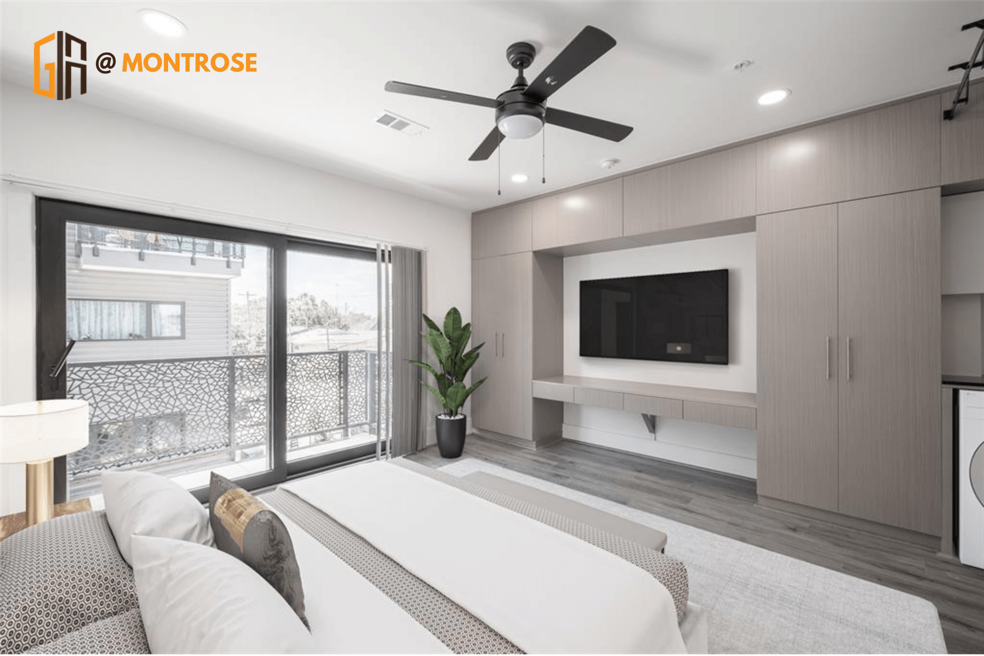 Modern luxury bedroom at Gia Montrose, a stylish Houston apartment with large window and wall-mounted TV.