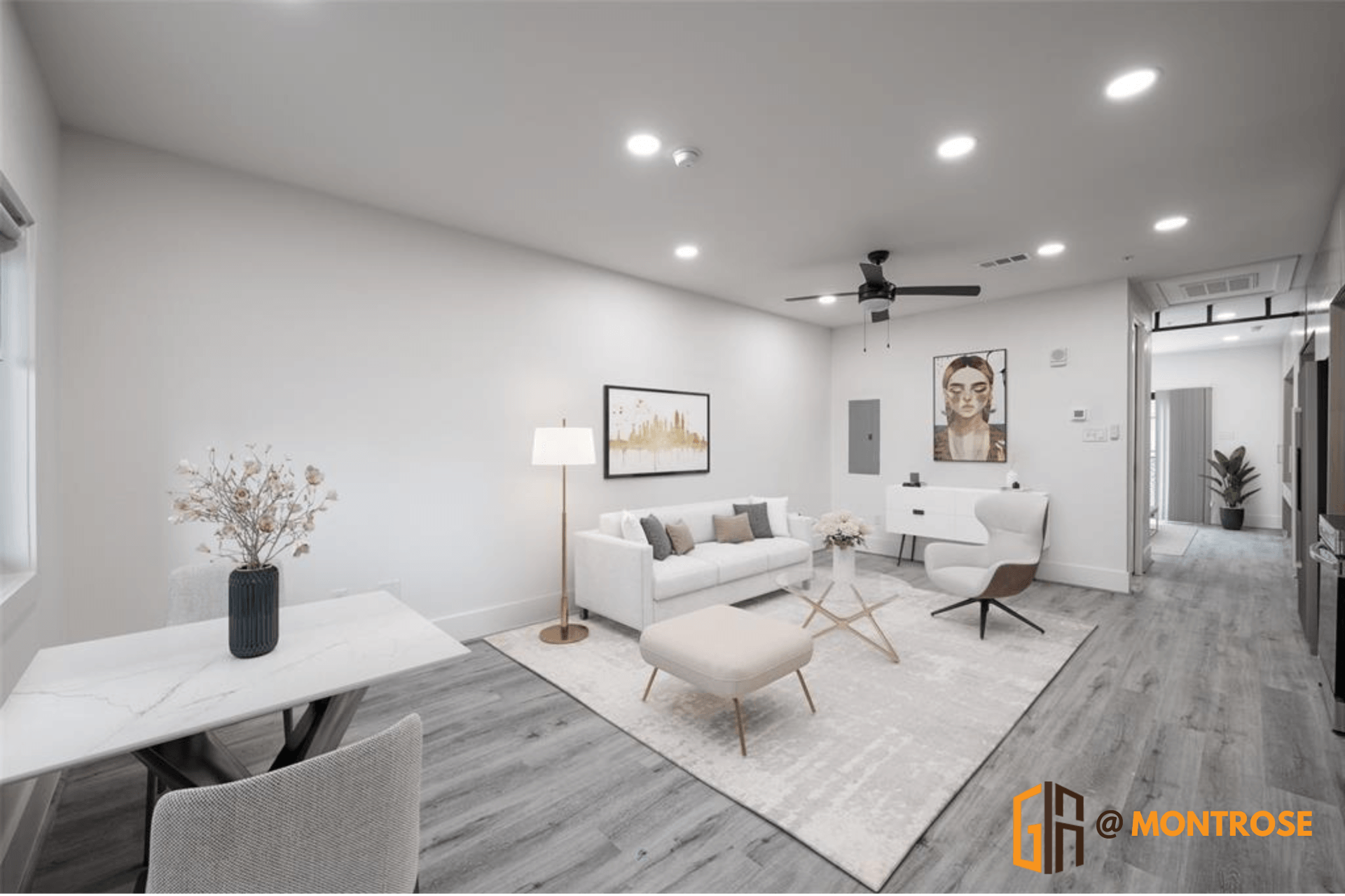 Bright, modern living room in our Houston apartments with a white sofa, decorative artwork, and a ceiling fan.