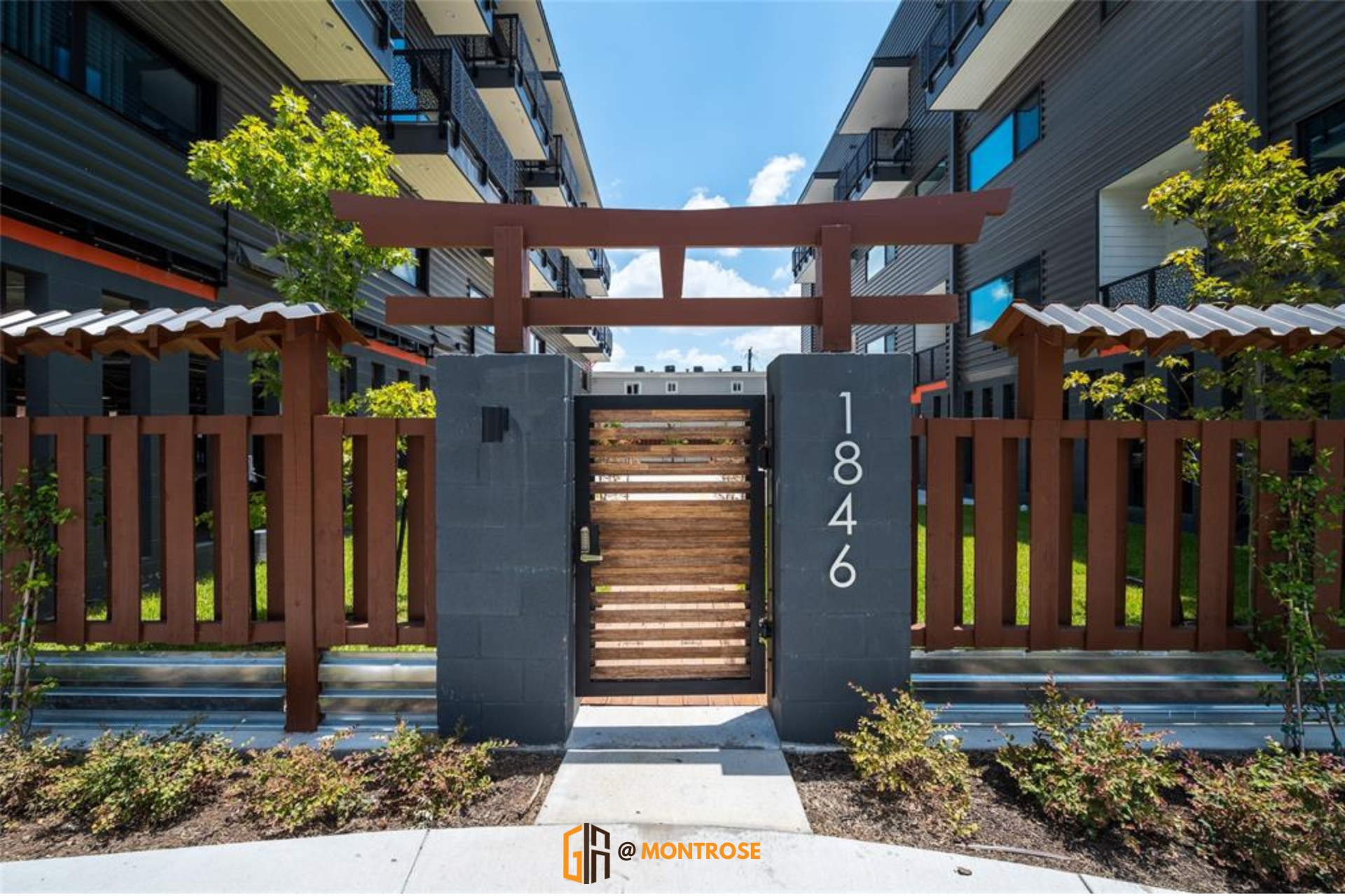 Modern entryway to a gated Houston apartment community at 1846, with a wooden gate and lush landscaping.
