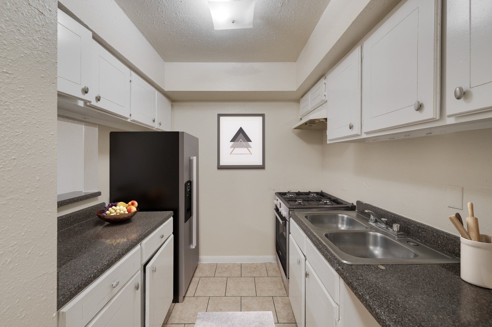Modern kitchen featuring a gas stove, double sink, and white cabinets in an apartment for rent in Houston.