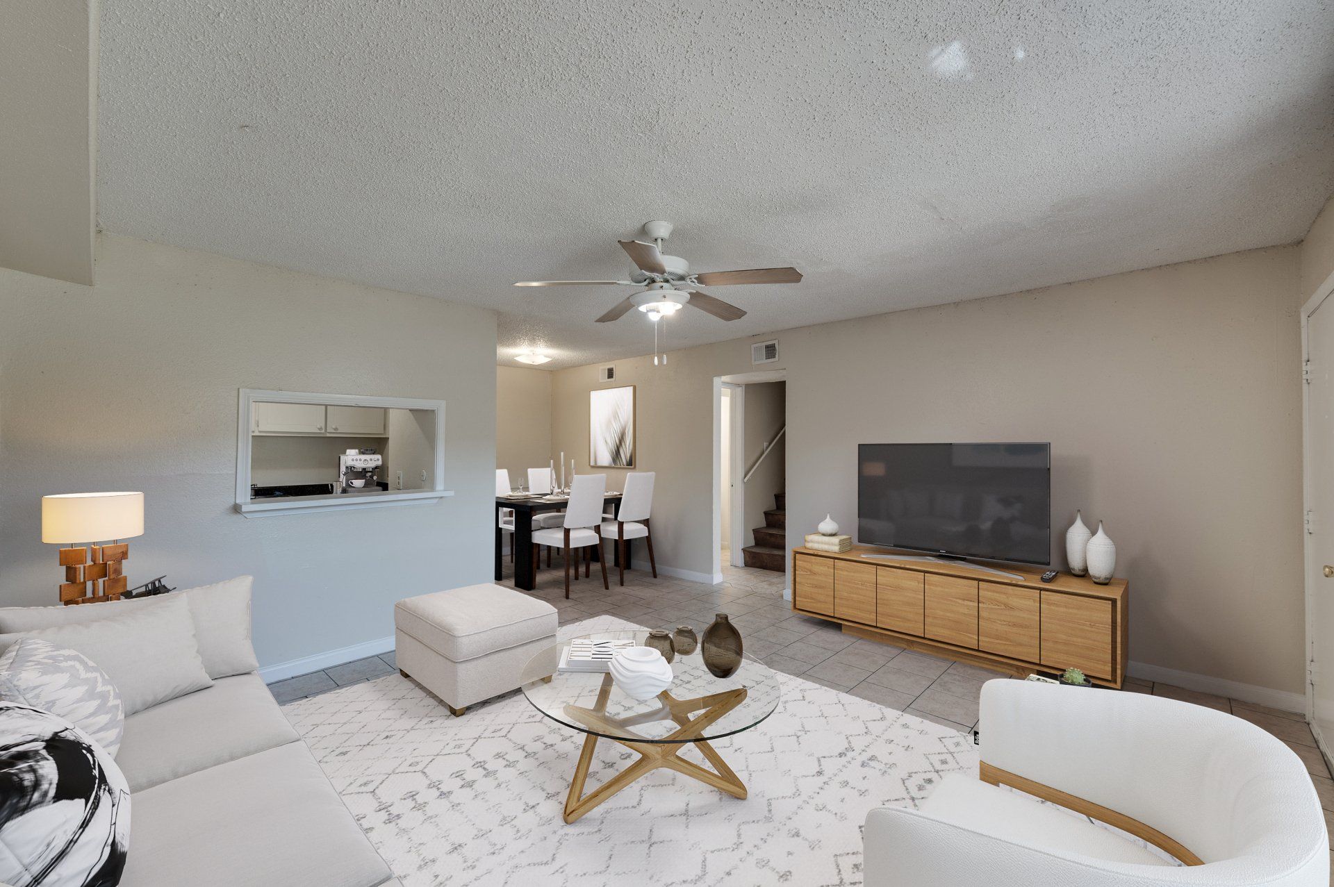 Well-lit, cozy, modern living room in Houston TX apartment rental. Open layout to dining, decorative artwork.