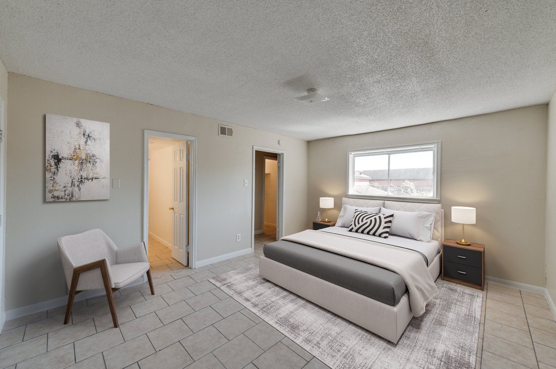 Spacious and cozy bedroom in a Houston, TX apartment, featuring a queen bed and a separate sitting area with a white sofa.
