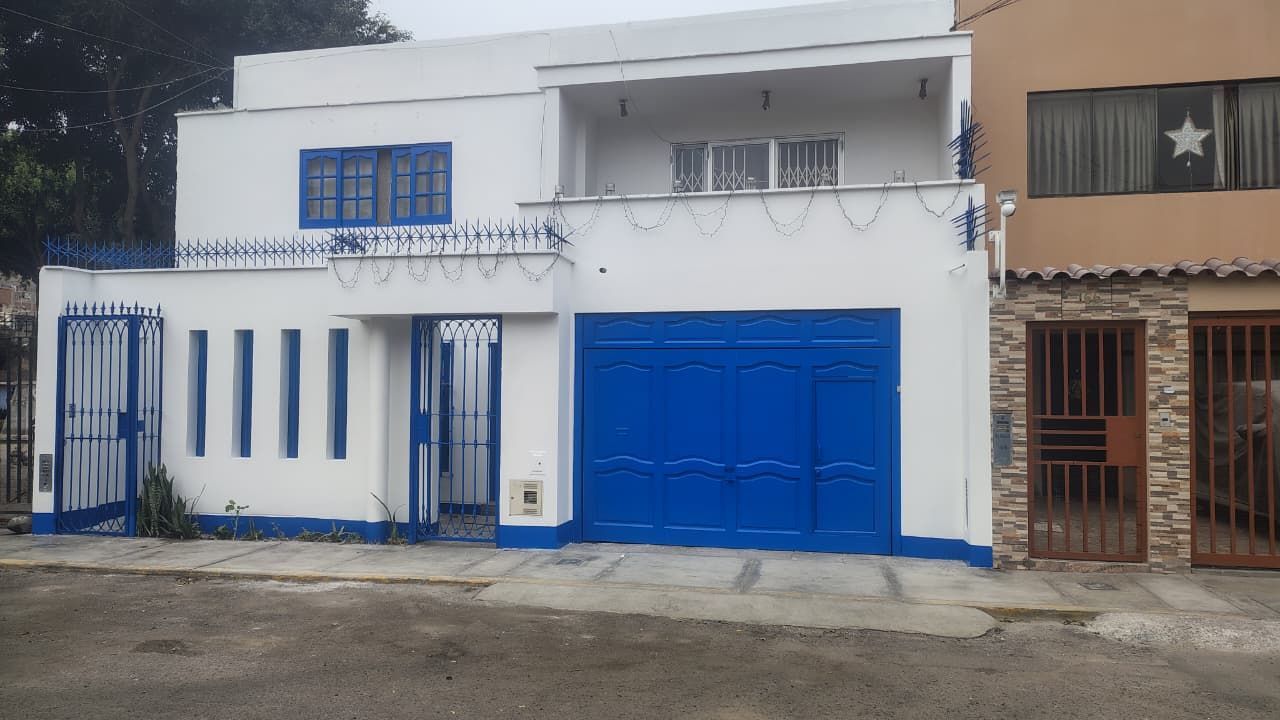 Casa blanca con detalles azules: puerta de garaje, molduras, portones y ventanas.