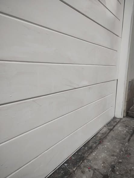 Pared de listones horizontales de color blanco junto a un marco de puerta de color blanco.