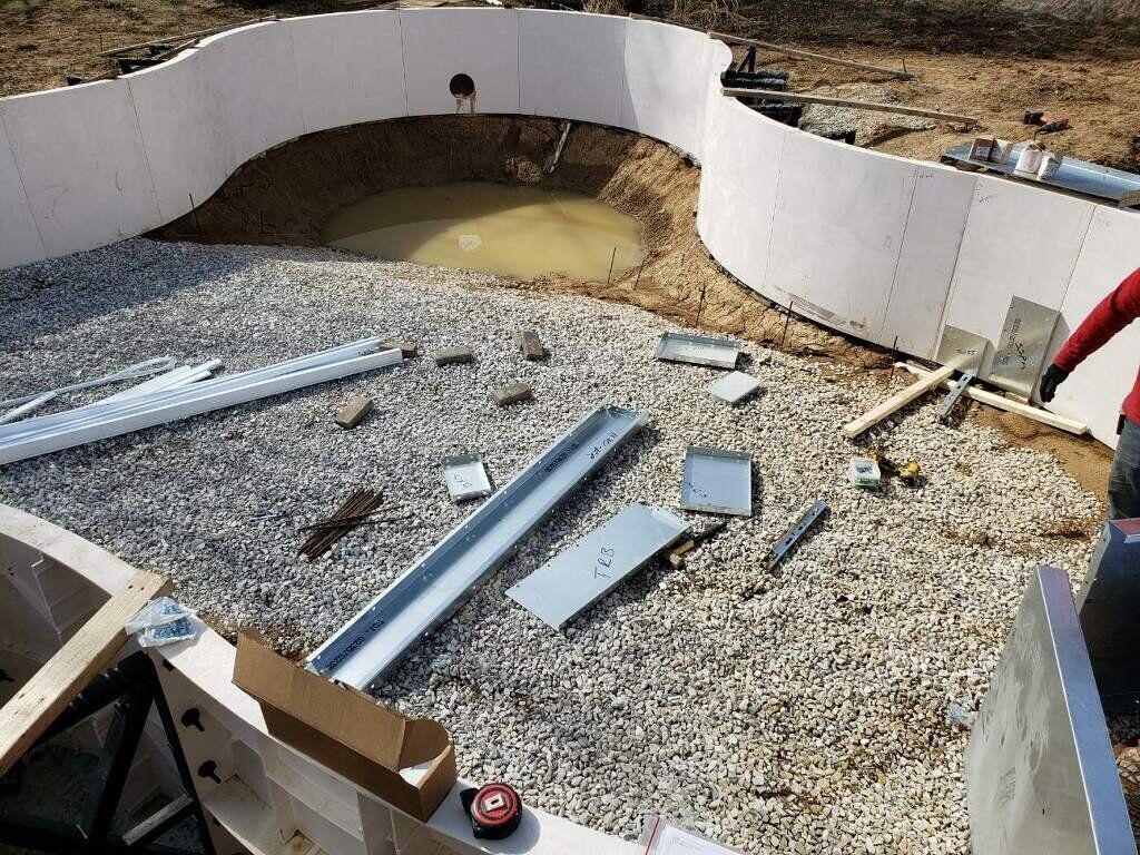 A man is working on a swimming pool in the dirt.