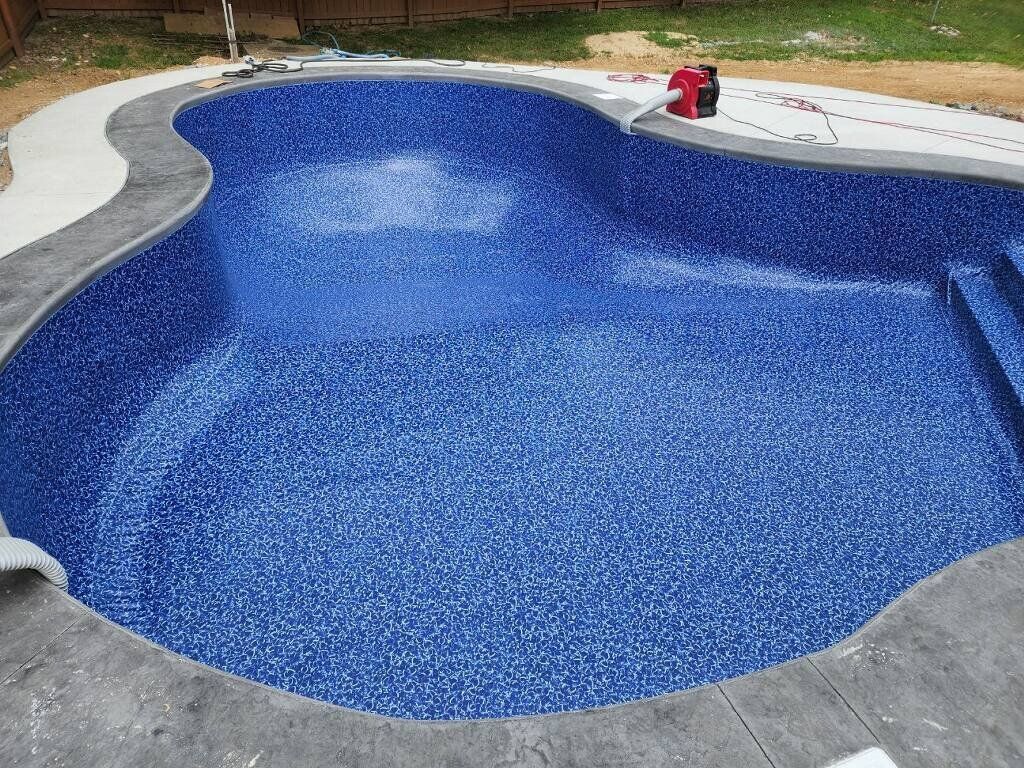 A large blue swimming pool is being built in a backyard.