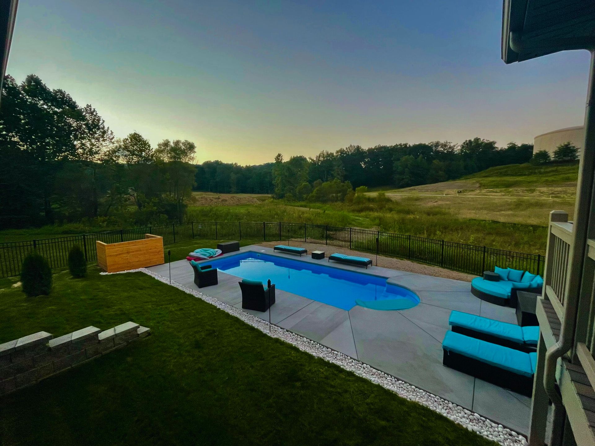 There is a large swimming pool in the backyard of a house.