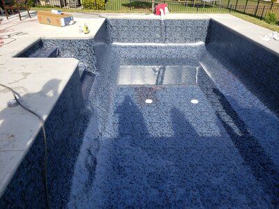 A large swimming pool is being built in a backyard.