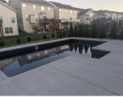 A large swimming pool is in the backyard of a house.