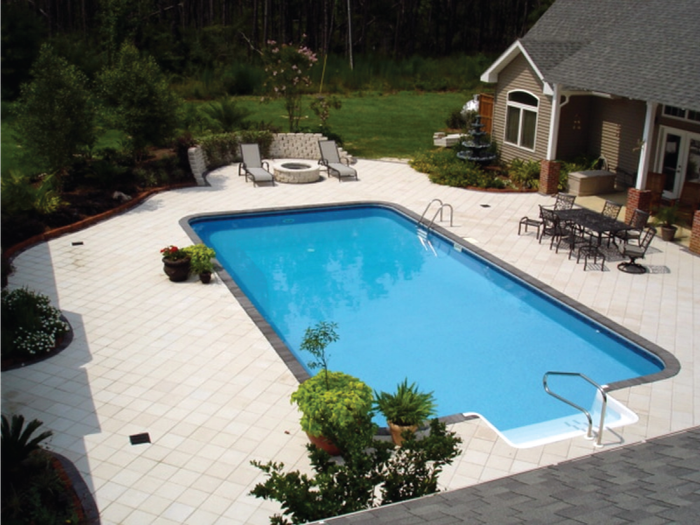 An aerial view of a large swimming pool with a house in the background