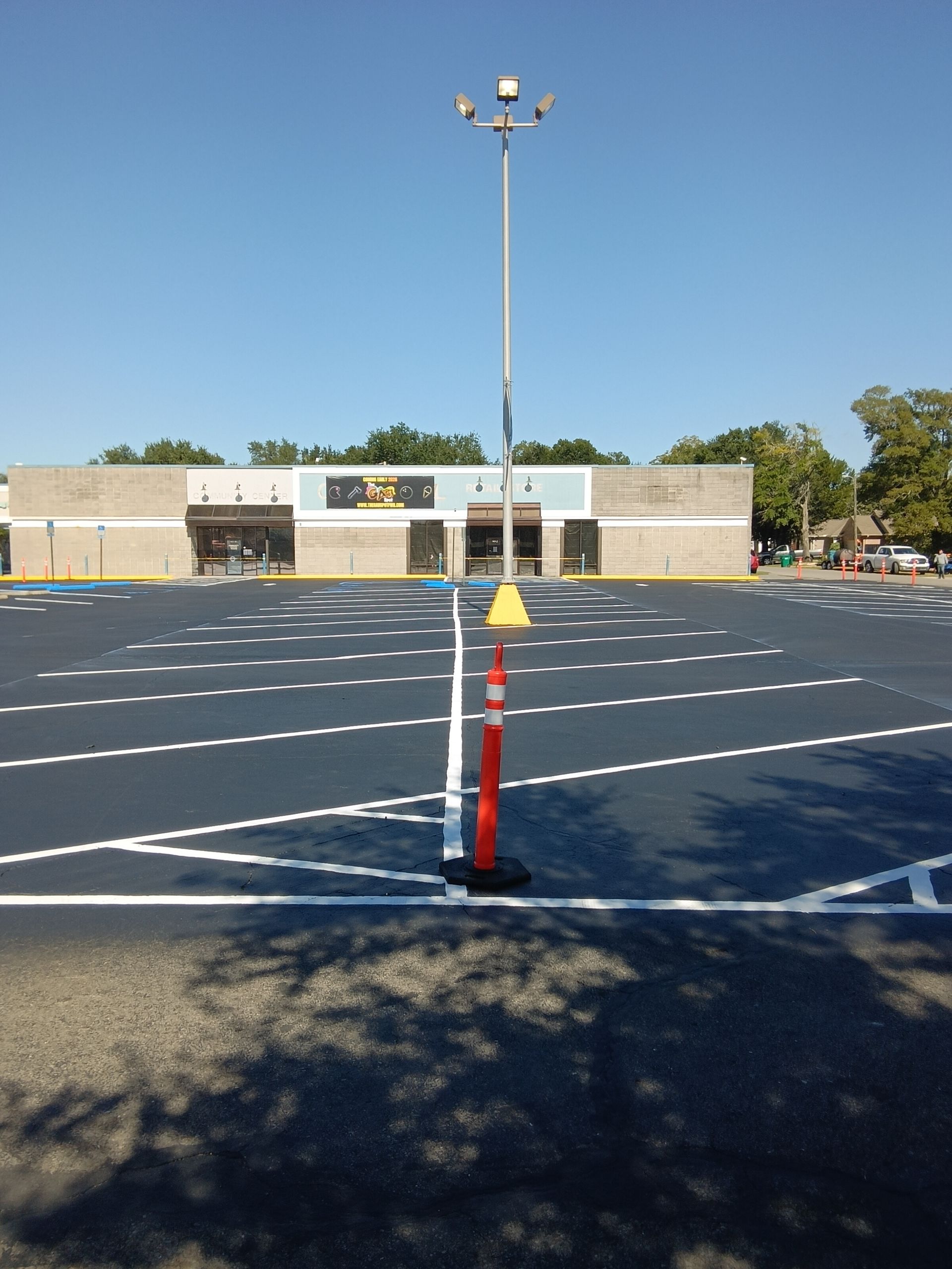 Empty parking lot with freshly painted blue asphalt and white parking space lines in front of a storefront.