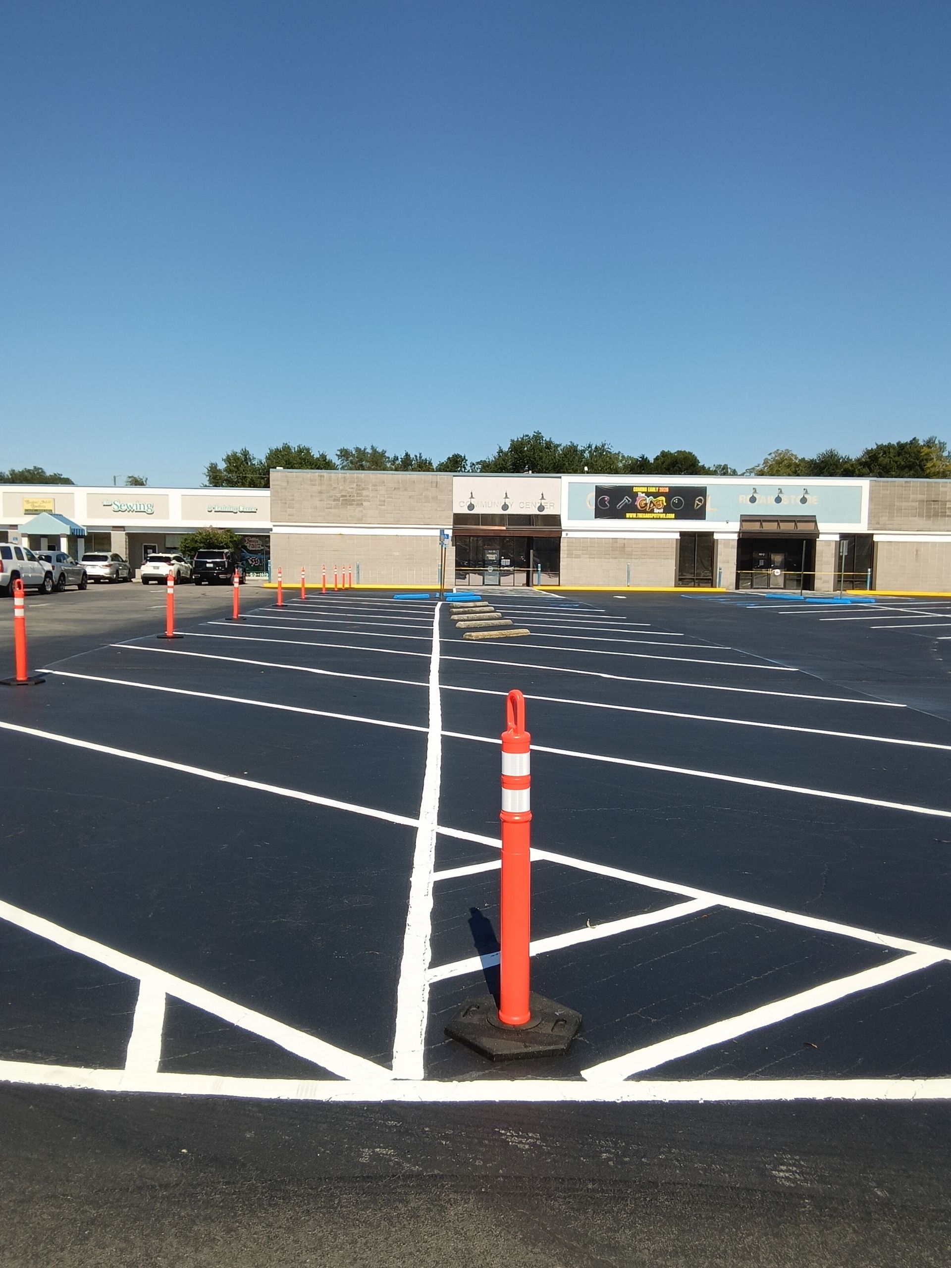 Newly paved parking lot with white painted lines and orange traffic cones.