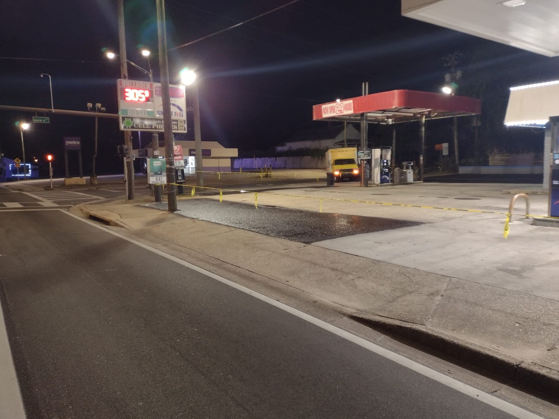 Gas station at night with a fuel truck under the canopy.