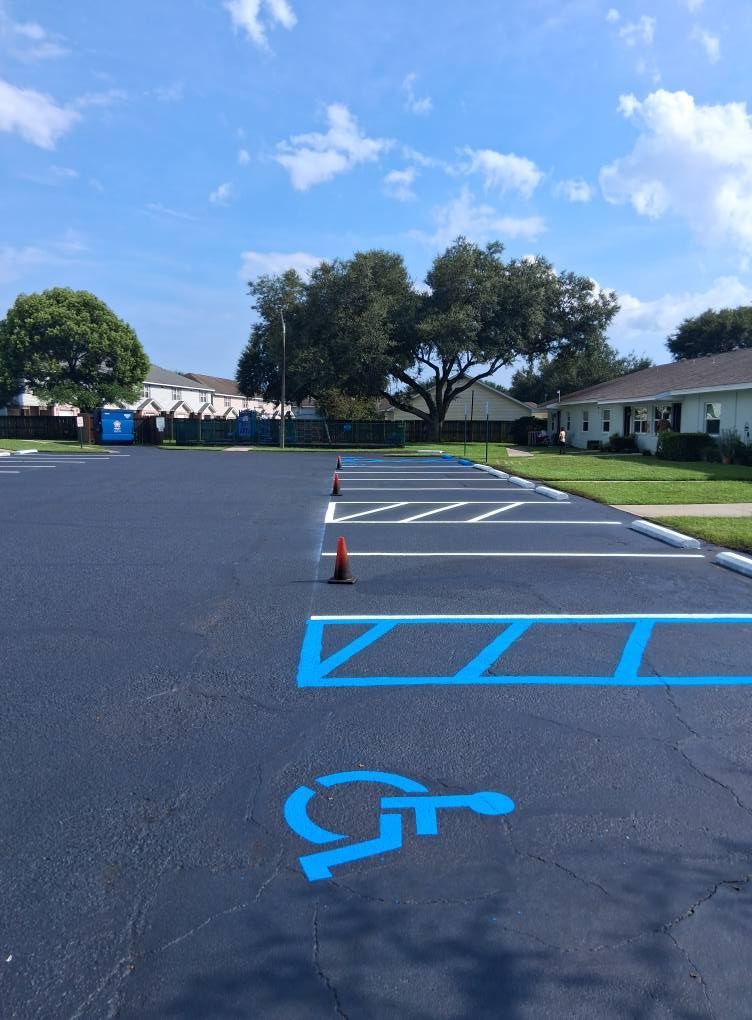 Blue painted handicap parking space in asphalt lot under a blue sky.
