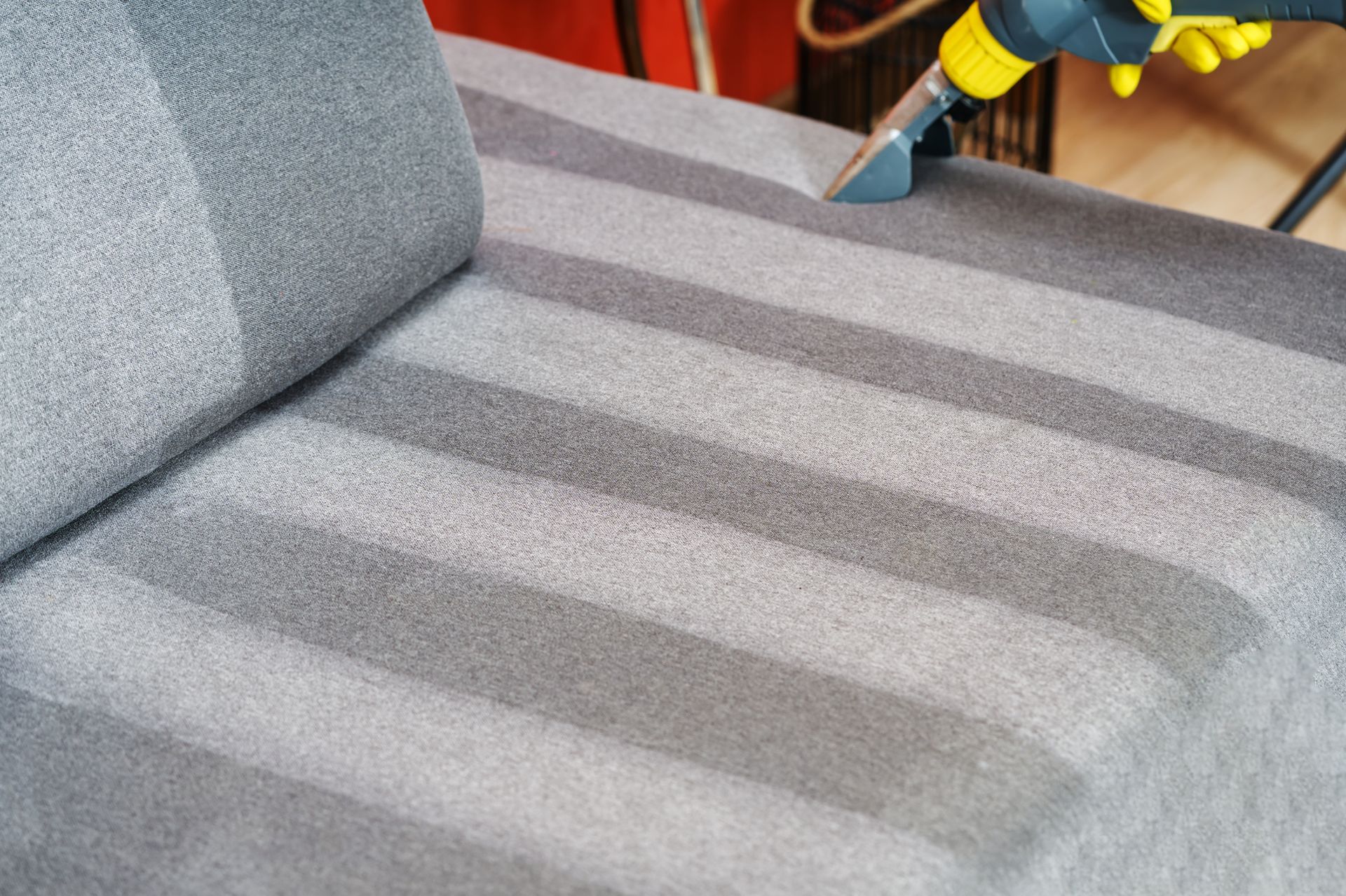Gray striped sofa cushion being cleaned with a handheld vacuum — Broadbeach Carpet Cleaning In Bundall, QLD